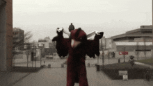 a person in a red and black costume is standing in front of a building