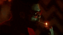 a man wearing sunglasses is smoking a cigarette with a lighter .