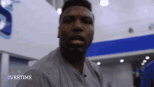 a man in a grey shirt with the word overtime on the bottom right