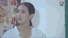 a woman in a striped shirt stands in front of a white wall