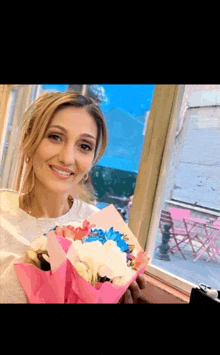 a woman is smiling while holding a bouquet of flowers in front of a window