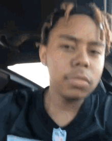 a young man with dreadlocks is sitting in the back seat of a car making a funny face .