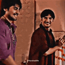 two men are standing next to each other smiling and laughing .