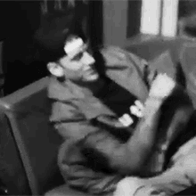 a black and white photo of a man and woman sitting next to each other .