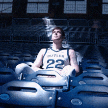 a man wearing a butler jersey sits in the bleachers