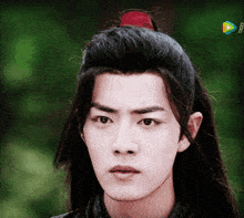 a close up of a young man 's face with a ponytail