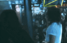 a man with long hair is singing into a microphone in front of a crowd in a dark room .