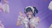 a girl singing into a microphone with a purple background