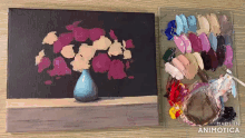 a painting of flowers in a blue vase next to a palette