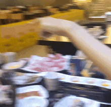 a blurry picture of a person taking a piece of meat from a plate