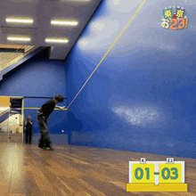 a man is swinging a racket in front of a blue wall with the number 01 03