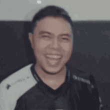 a man in a black and white shirt is smiling and making a funny face .