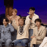 a group of young men are sitting on a couch and waving their hands .