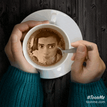 a person is holding a cup of coffee with a picture of a boy on it