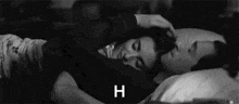 a black and white photo of a man and a woman hugging each other in bed .