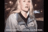 a woman in a jacket is standing in front of a car and says mina olin paugu otsas , kui puu kais