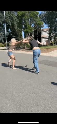 two women are standing next to each other on the side of a road .