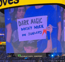 a boy holds a sign that says dark magic does n't work on sundays