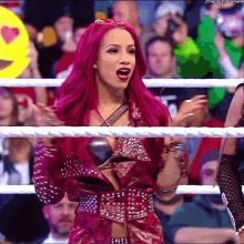 a woman with pink hair is standing in a ring with a crowd behind her