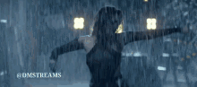 a woman in a black dress is walking in the rain with the words @dmstreams written below her