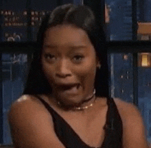 a woman in a black tank top is making a funny face .
