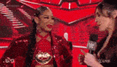 two women are talking to each other in front of a microphone on a stage .