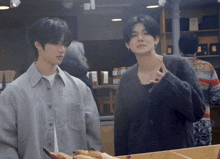 two young men standing next to each other in a bakery
