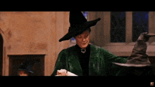 a woman wearing a witch hat is holding a piece of paper .