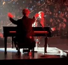 a man playing a piano in front of a crowd with his arms outstretched