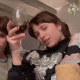 a woman is holding a glass of red wine