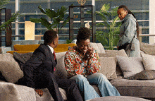 a man in a suit sits on a couch next to a woman laughing