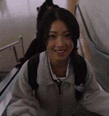 a girl is smiling while riding an escalator with a backpack on her back