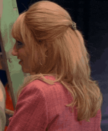 a woman with blonde hair is wearing a pink jacket and earrings