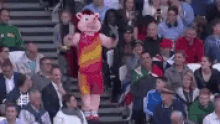 a mascot is standing in the middle of a crowd of people .