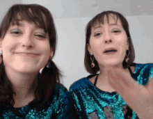 two women wearing blue sequined tops are making faces