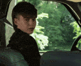 a young boy with a mohawk sits in a car