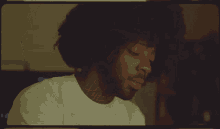 a man with curly hair and a beard wearing a white shirt