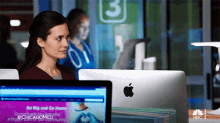 a woman sits at a desk with an apple computer