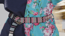 a woman wearing a blue and pink floral dress with a moschino belt around her waist