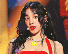 a woman wearing a red dress and a necklace with a yellow flower on it