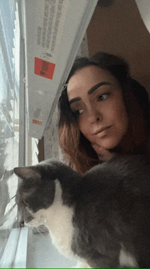 a woman and a cat are looking out a window with a sticker on the window that says " warning "