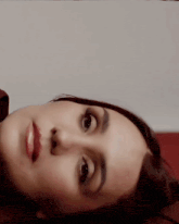 a close up of a woman 's face with a white wall in the background