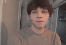 a young man with curly hair is looking at the camera