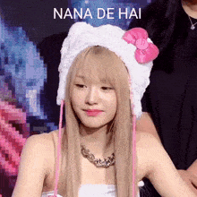 a girl wearing a hello kitty hat and a necklace with the words nana de hai written above her