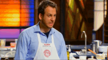 a man wearing a white apron with the letter m on it