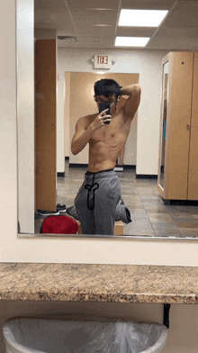 a man taking a picture of himself in front of a mirror with an exit sign above it