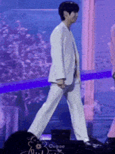 a man in a white suit is walking on stage .