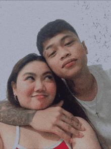 a man and a woman are posing for a picture and the man has a cross necklace on his neck
