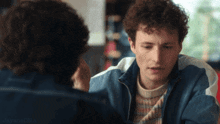 a man with curly hair is looking at another man