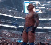 a shirtless wrestler stands in front of a crowd with the letters jh on the jumbo tron